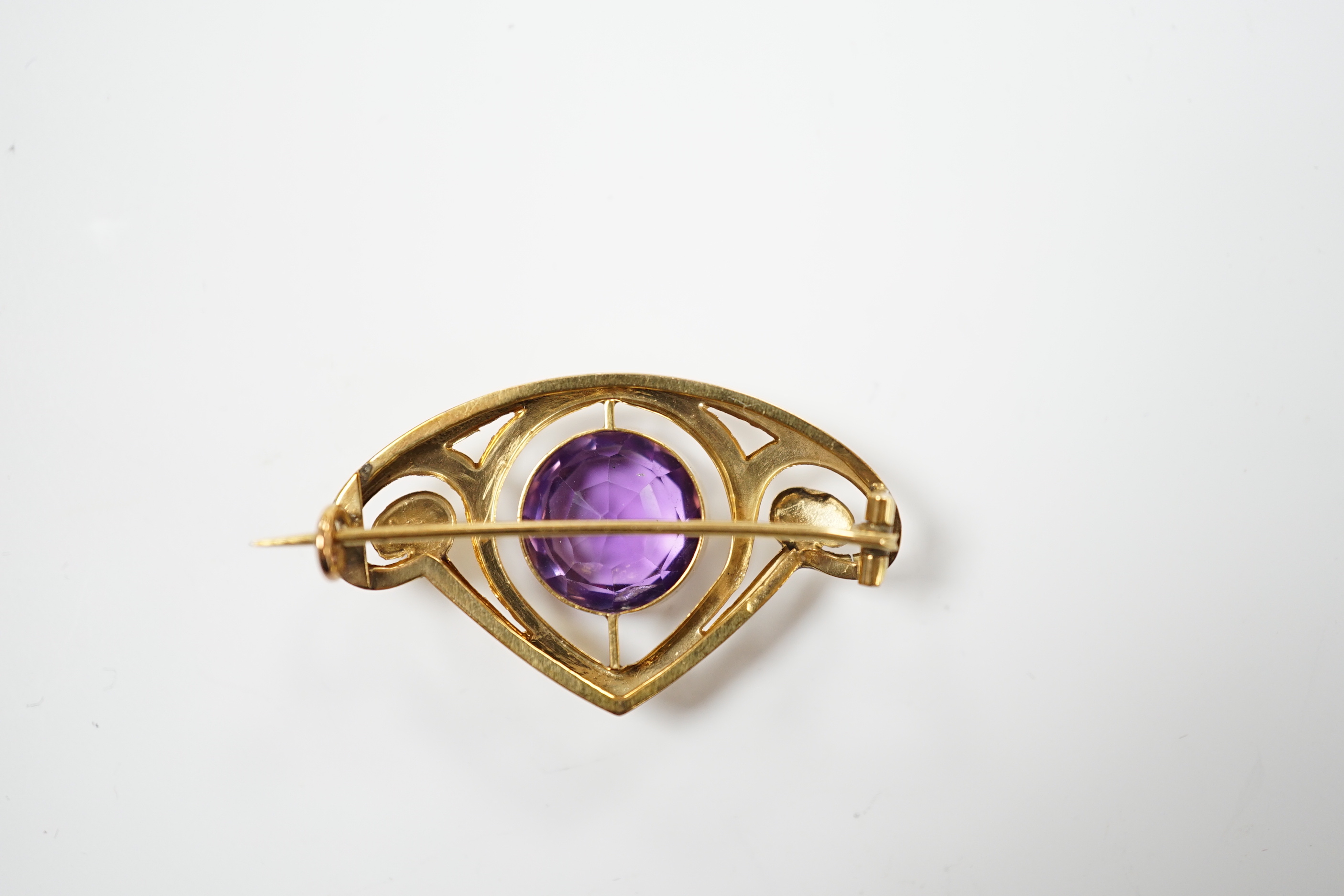 An Art Nouveau style yellow metal and single stone round cut amethyst set brooch, 35mm, gross weight 3.4 grams.